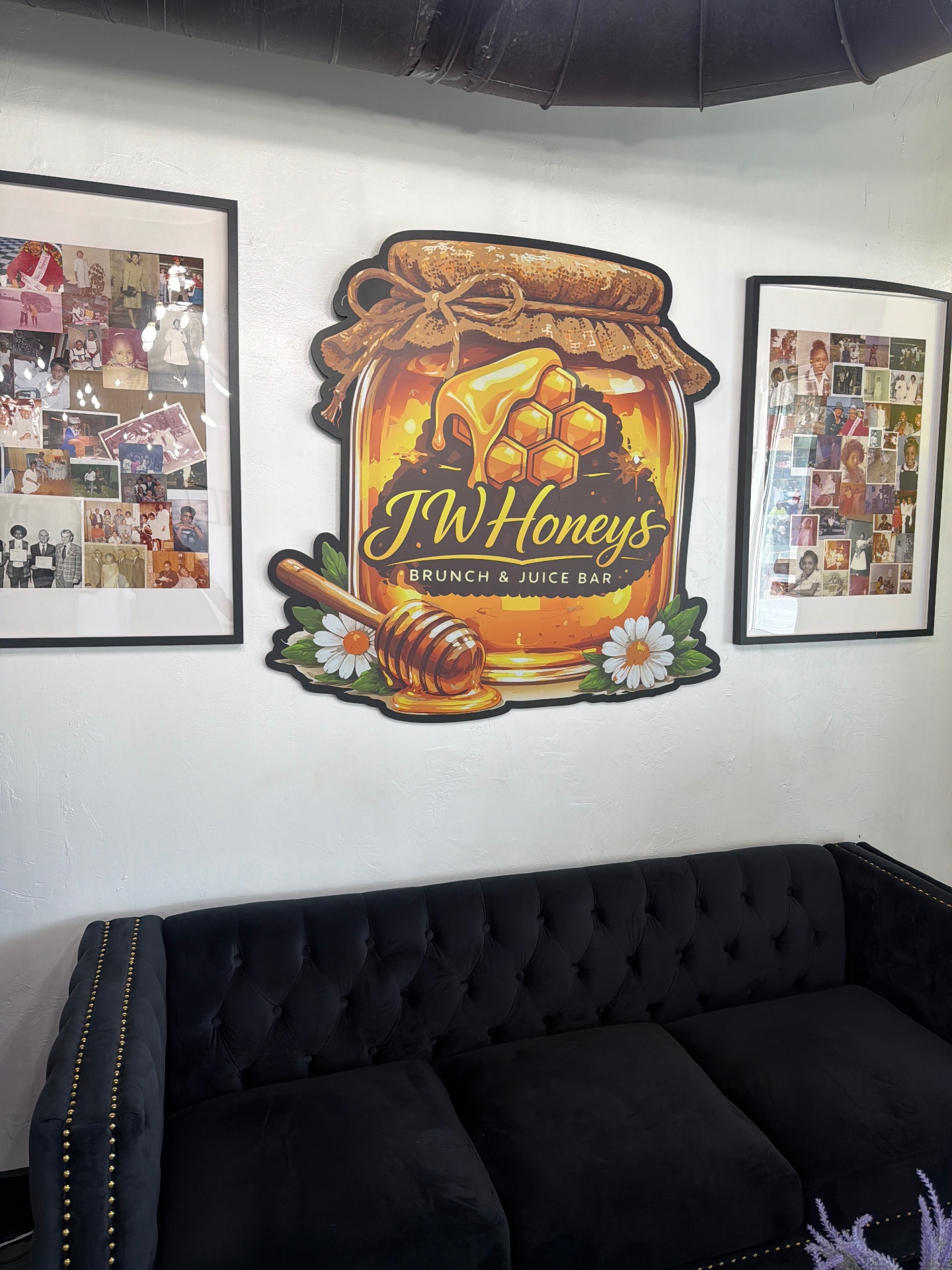 JW Honeys logo wall above a velvet sofa with framed family photos