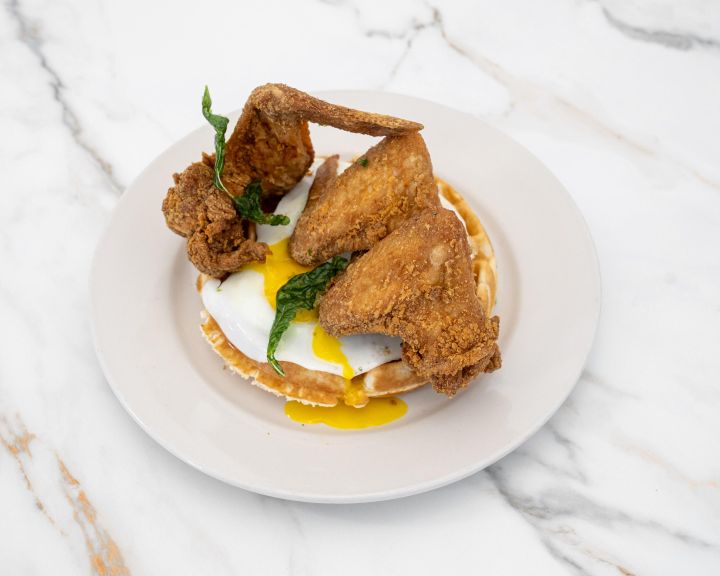 Fried chicken and waffle topped with a runny egg
